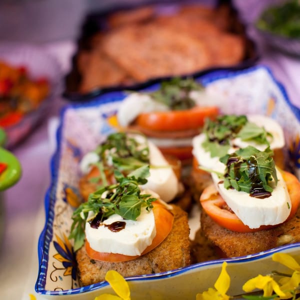 Close-up of breaded chicken cutlets topped with tomato, mozzarella, arugula, and balsamic glaze.