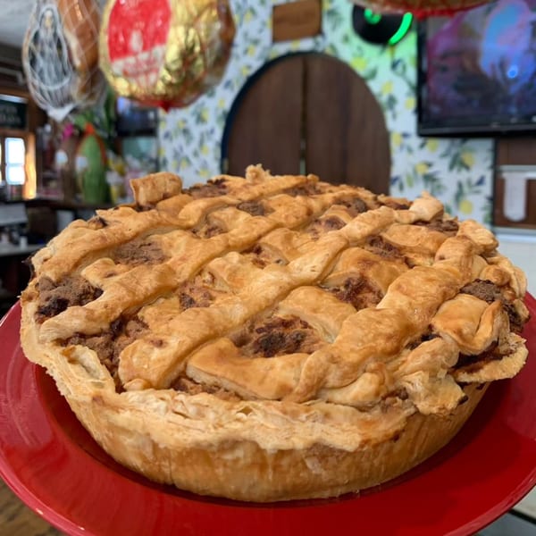 A golden-brown lattice-top pie with a rich, dark filling, served on a vibrant red plate.