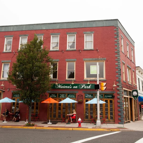 Matera's on Park, a red brick building with outdoor seating under blue and orange umbrellas.